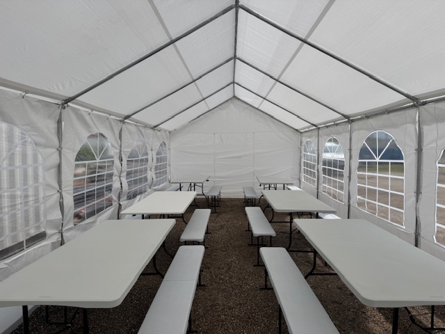 Intérieur d'une tente de réception avec tables et bancs